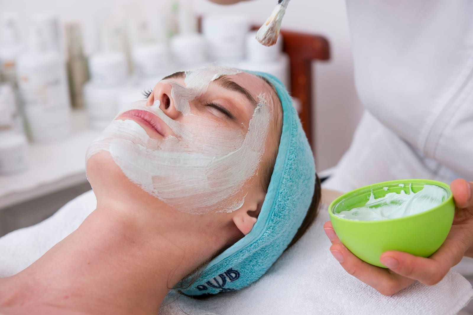 Esthéticienne appliquant un masque sur le visage d’une cliente allongée