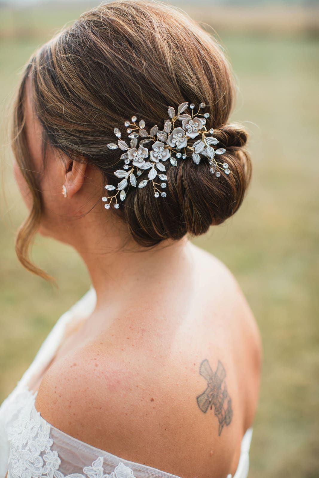Chignon de mariée avec peigne fleuri, épaules dégagées